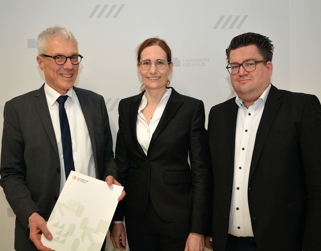 Der Kanzler der Universität Bielefeld Dr. Stephan Becker (l.) übergibt Univ.-Prof. Dr. Claudia Scherl (Mitte) ihre Ernennungsurkunde im Beisein von Bernd Henkemeier, kaufmännischer Direktor des Klinikum Bielefeld (r.).