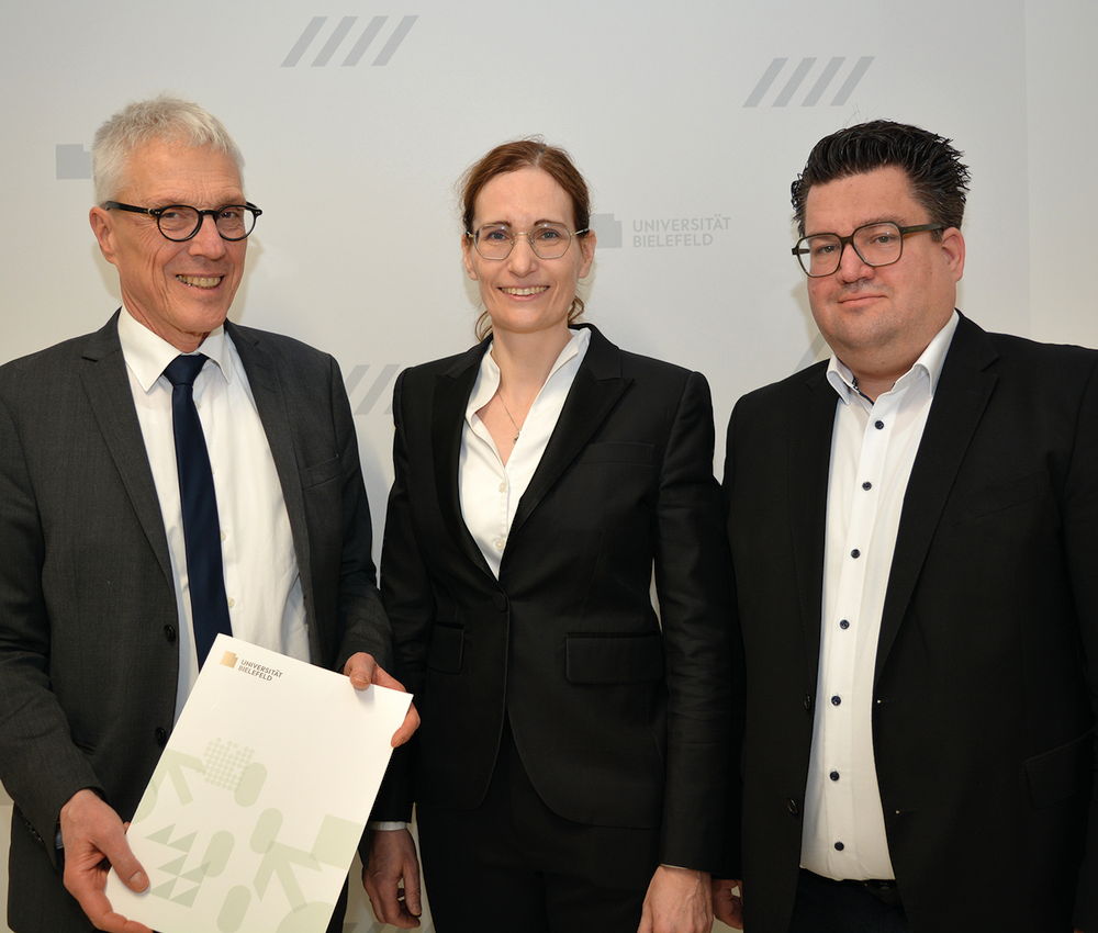 Der Kanzler der Universität Bielefeld Dr. Stephan Becker (l.) übergibt Univ.-Prof. Dr. Claudia Scherl (Mitte) ihre Ernennungsurkunde im Beisein von Bernd Henkemeier, kaufmännischer Direktor des Klinikum Bielefeld (r.).