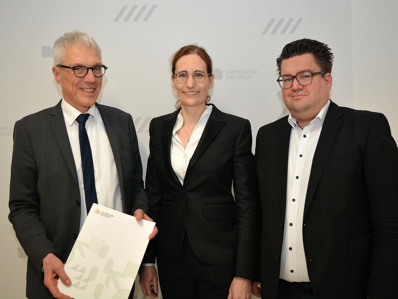 Der Kanzler der Universität Bielefeld Dr. Stephan Becker (l.) übergibt Univ.-Prof. Dr. Claudia Scherl (Mitte) ihre Ernennungsurkunde im Beisein von Bernd Henkemeier, kaufmännischer Direktor des Klinikum Bielefeld (r.).